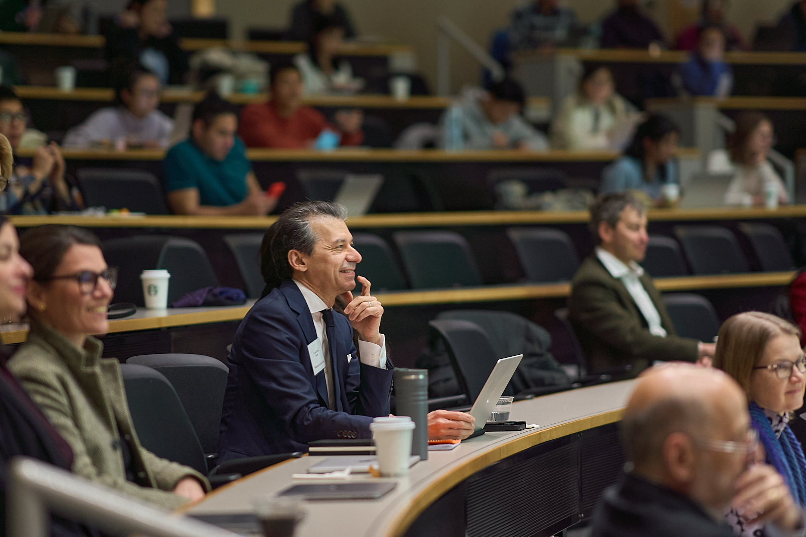 Azad Bonni smiles while sitting in an auditorium.