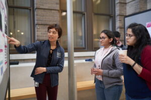 Woman discussing a scientific poster to two viewers