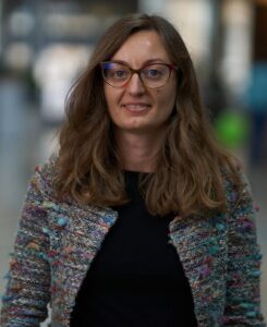 Gaia Tavoni is a woman with glasses and long brown hair.