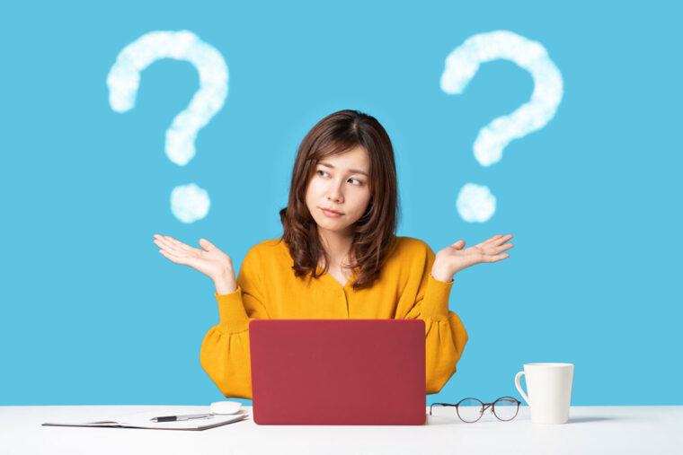 Woman sitting at a laptop with two illustrated question marks next to her head