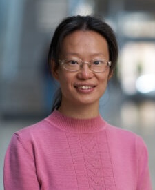 Yao Chen is a woman wearing glasses and a pink top.